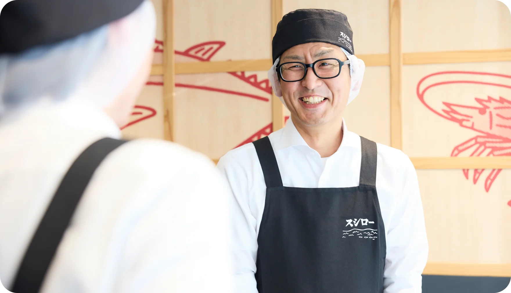 スタッフと向かい合って笑顔で話す花輪博行