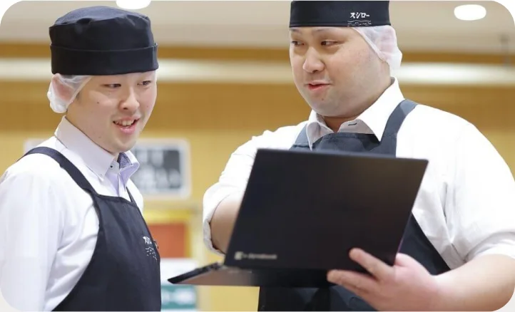ノートパソコンを見ながら話し合う2人の社員